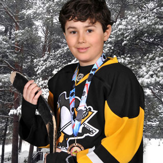 Young boy hockey player posing in front of snowy scene