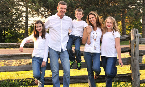 Portrait of family posing in front of fence