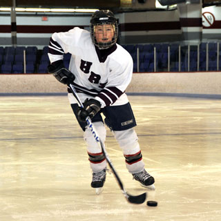 Young boy hockey player skating towards camera